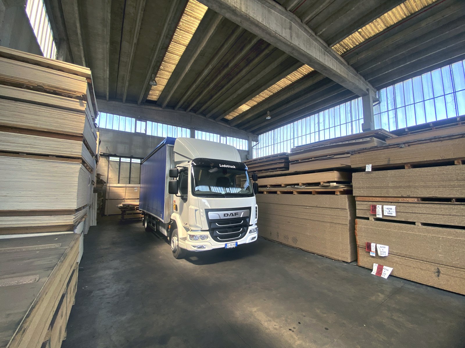 Camion in carico fra le pile di pannelli, nel magazzino di Carugo